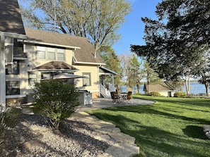 Une maison à deux étages avec un patio, une petite terrasse et une vue sur un lac.