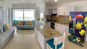 A modern kitchen with a central island, a grey sofa with colorful cushions, and a dining area with a view to the outside. - 2P1-AL4 APARTAMENTO DE 2 ALC CON AIRE A. (Cartagena)