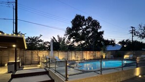 A swimming pool with a wooden deck, steps leading to the pool, and lounge chairs. - Austin Lux 4BR w/Wellness Center-Heated Pool/Sauna & Cold Plunge in Westlake (Austin)