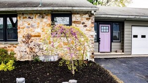 A stone house with a garden, a purple door, and a garage. - Cozy farmhouse with views and amenities! Pet-friendly, baby goats and chickens! (Grantville)
