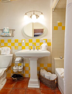 Une salle de bain avec un lavabo blanc, deux robinets, un miroir et un porte-serviettes.