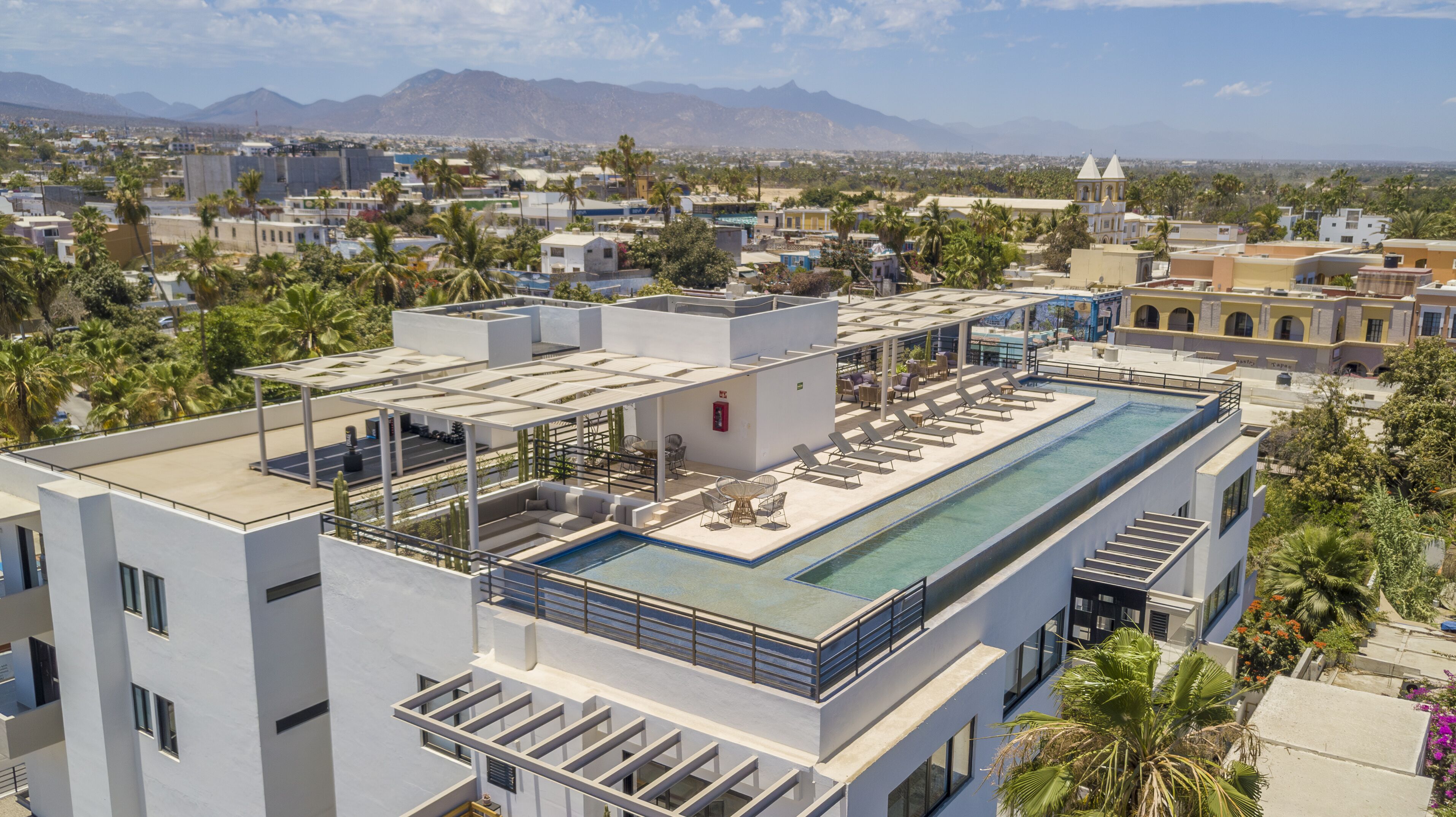 A rooftop pool with lounge chairs and a view of the cityscape and mountains.