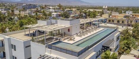 A rooftop pool with lounge chairs and a view of the cityscape and mountains.