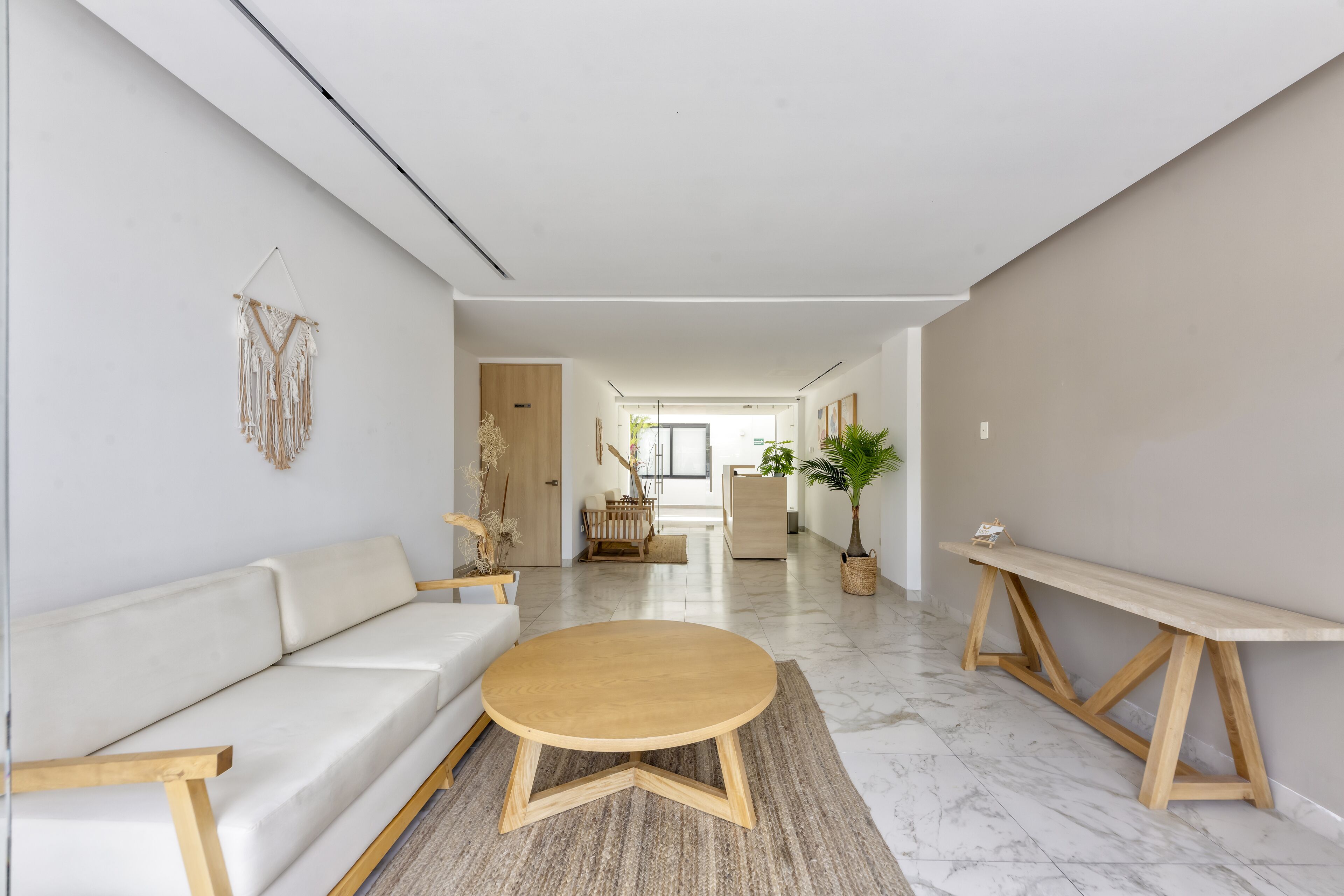 A modern living room with a white sofa, a wooden coffee table, and a wooden bench.