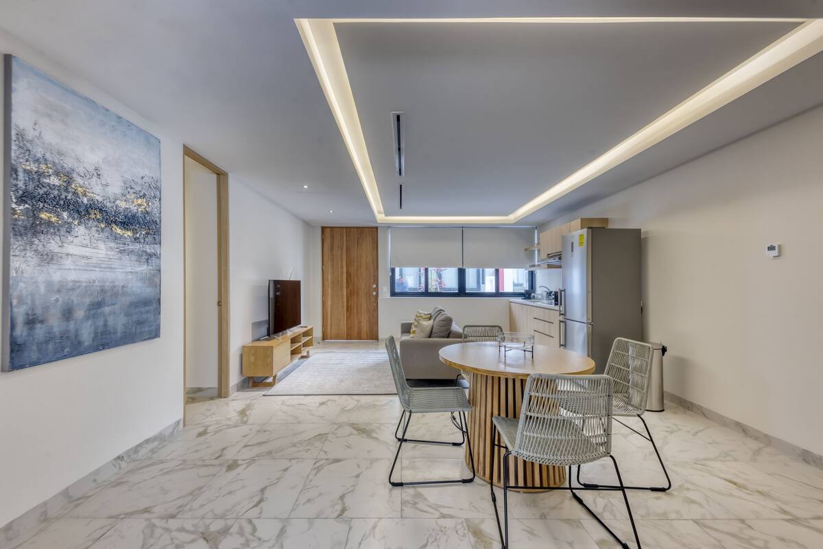 A modern living room with a marble floor, a round wooden dining table, and contemporary chairs.