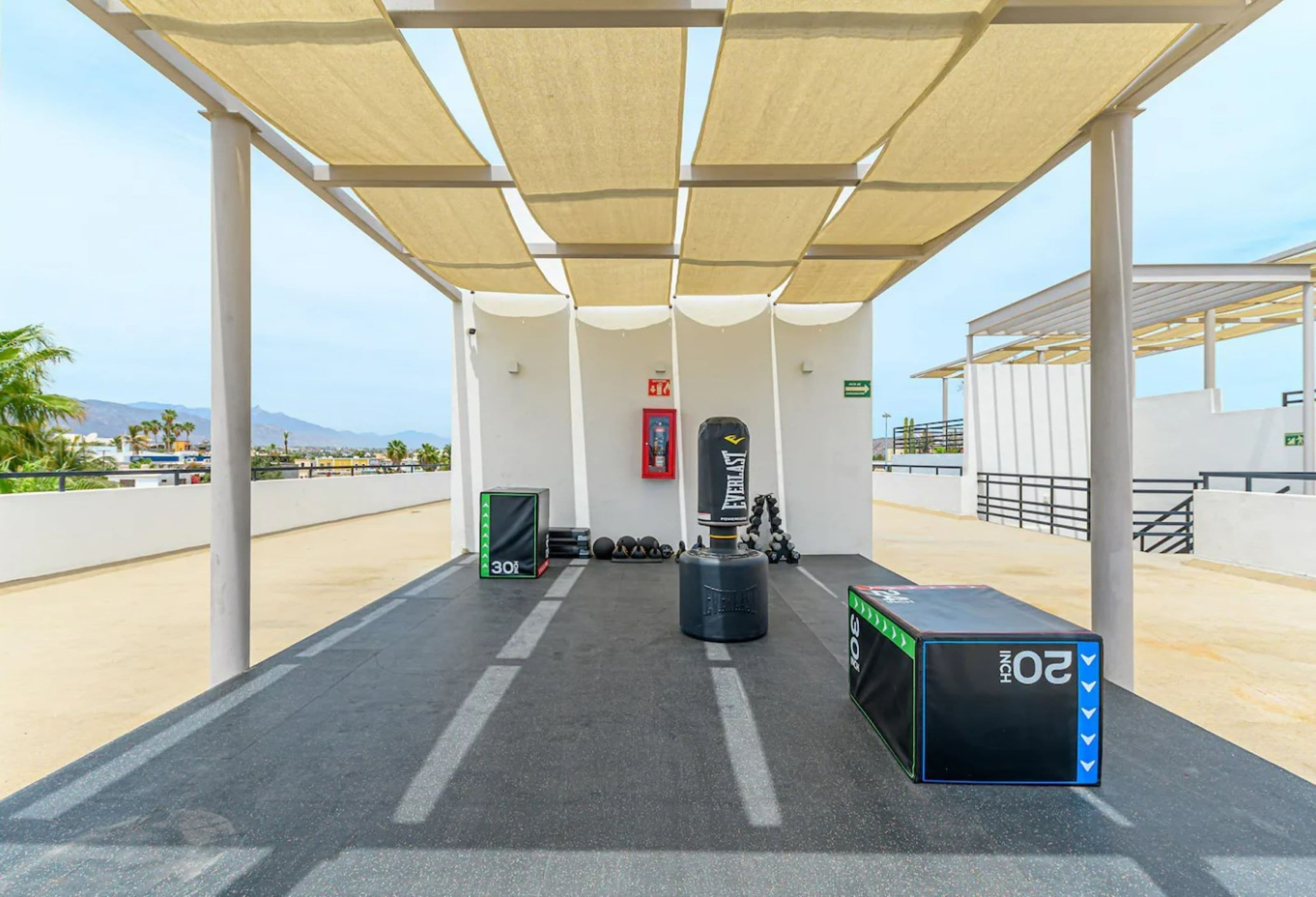 An outdoor gym area with exercise equipment, a punching bag, and a weight bench.