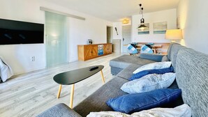 Una sala de estar moderna con un sofá gris, una mesa de centro negra y un mueble de madera.