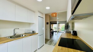 Una cocina moderna con armarios blancos, un lavamanos de acero inoxidable y una placa de inducción negra.