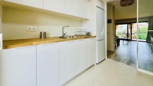 Una cocina moderna con armarios blancos, encimera de madera, pileta de acero inoxidable y refrigerador empotrado.