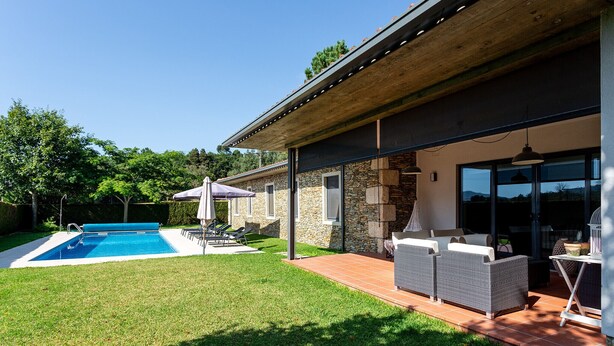 Ein modernes Haus mit Schwimmbad, Außenbereich mit Sitzgelegenheiten und einer überdachten Terrasse.