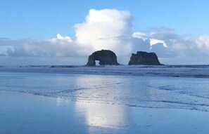 Una playa con dos formaciones rocosas y cielo despejado.