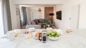 Una sala moderna con sofá, mesa de centro y zona de comedor con alimentos para el desayuno.
