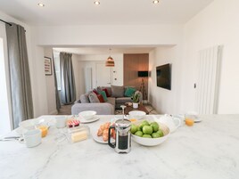 A modern living room with a sofa, coffee table, and a dining area with breakfast items.