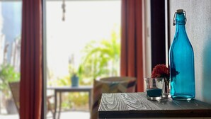 Una stanza con un tavolo di legno, una bottiglia blu e un bicchiere con un fiore.