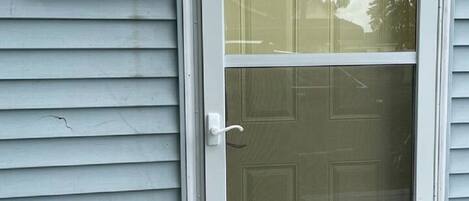 A house number sign '301B' mounted on a light gray siding wall, a white door with a glass panel, and a small wall-mounted light fixture.