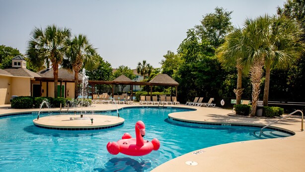 A pool area with a fountain, lounge chairs, and palm trees. - 2 BR Dog-Friendly Condo W/ Free Golf Cart, Pool and Other Resort Amenities (Myrtle Beach)