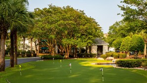 A well-maintained golf course with a clubhouse, surrounded by lush greenery and palm trees. - 2 BR Dog-Friendly Condo W/ Free Golf Cart, Pool and Other Resort Amenities (Myrtle Beach)
