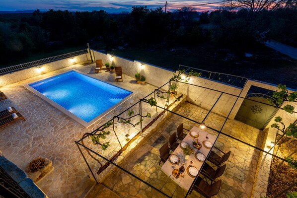 A rooftop pool area with a stone floor, a pool, and a dining setup with chairs and tables. - Seven Olives Guest House **** with heated pool - Krka waterfalls - near Sibenik (Gornje Planjane)