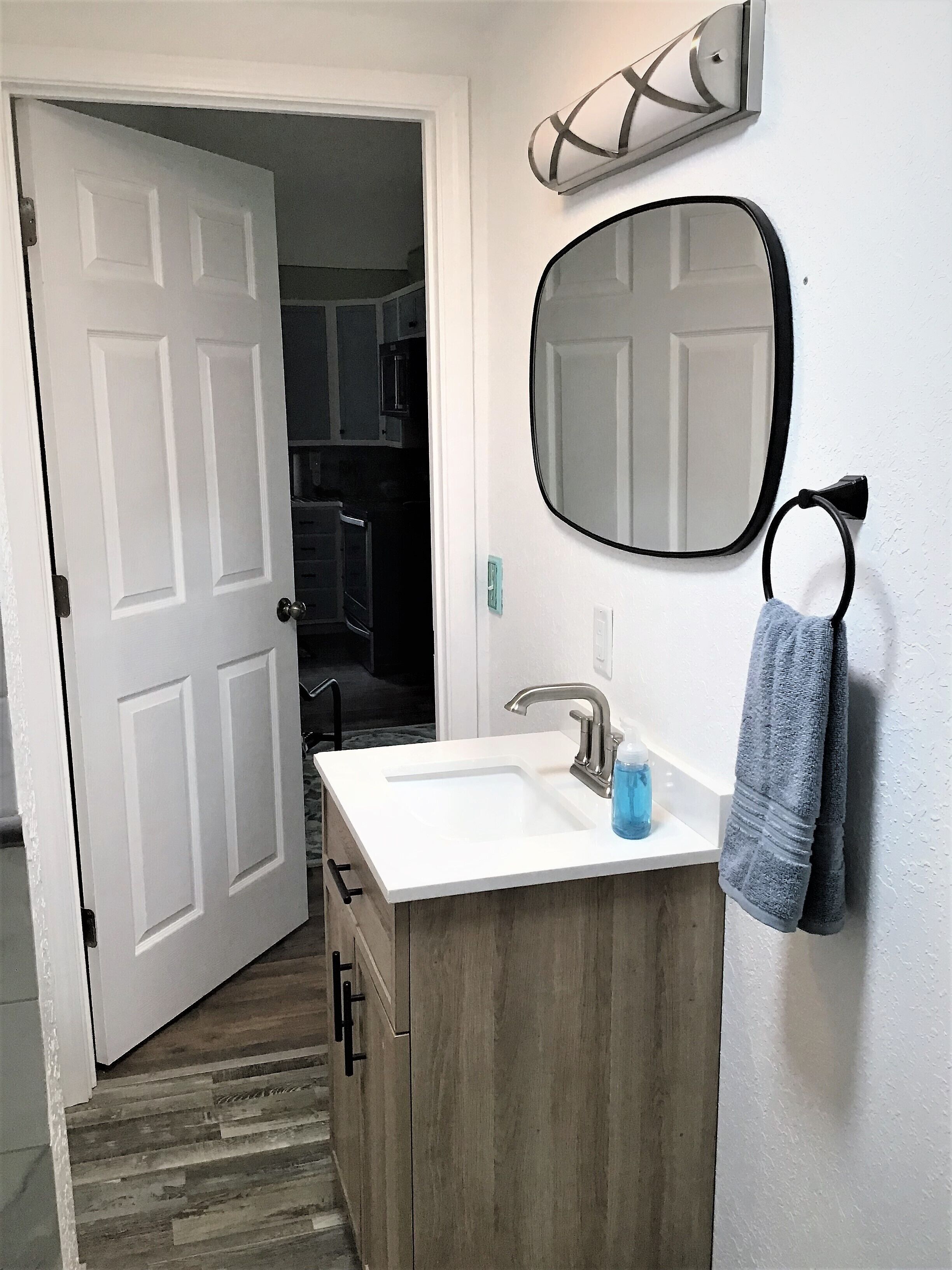 Un baño con un lavabo blanco, un espejo y un toallero.