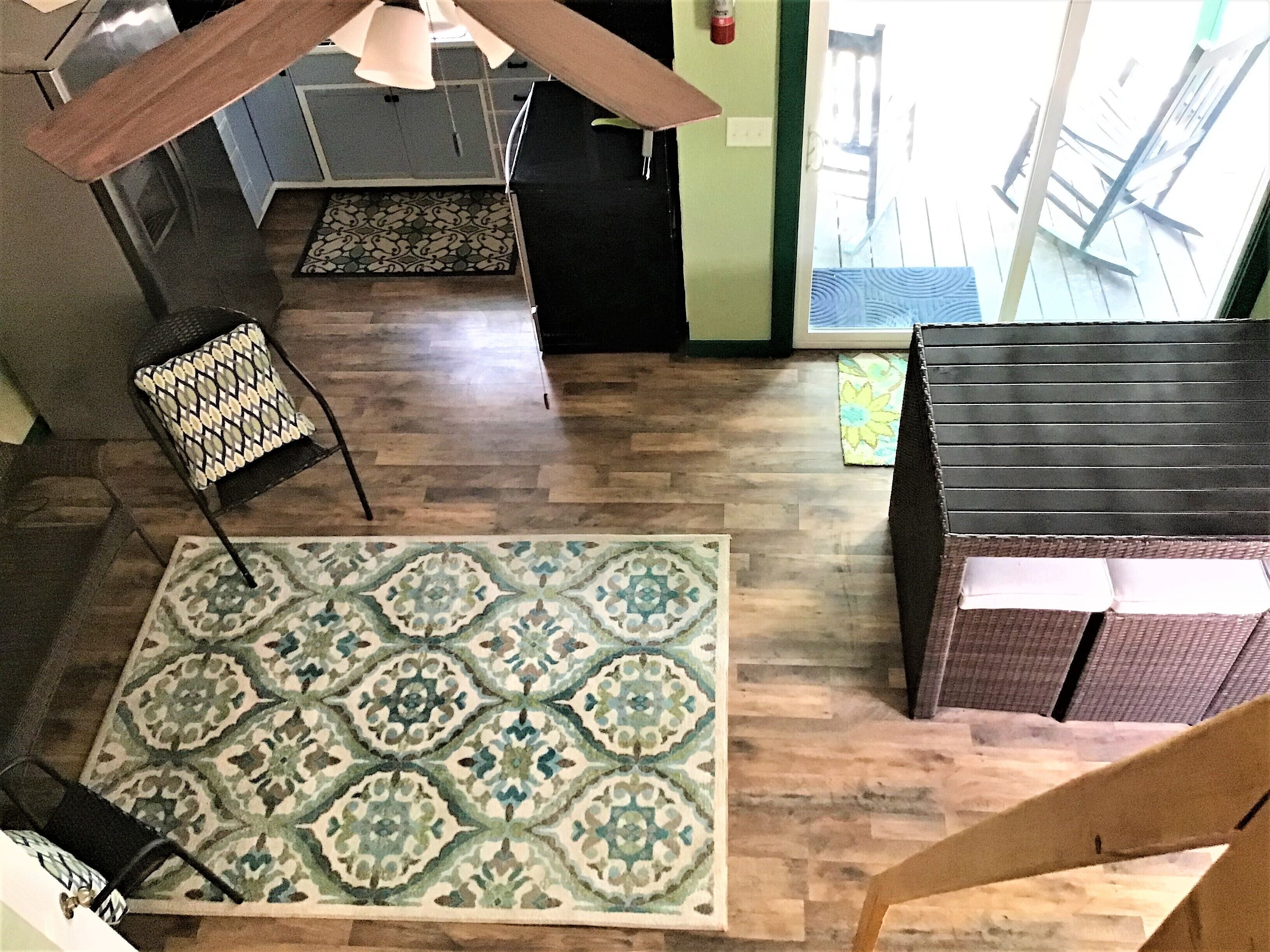 Una habitación amplia con un tapete grande estampado, un banco de madera y una silla con cojín decorado.