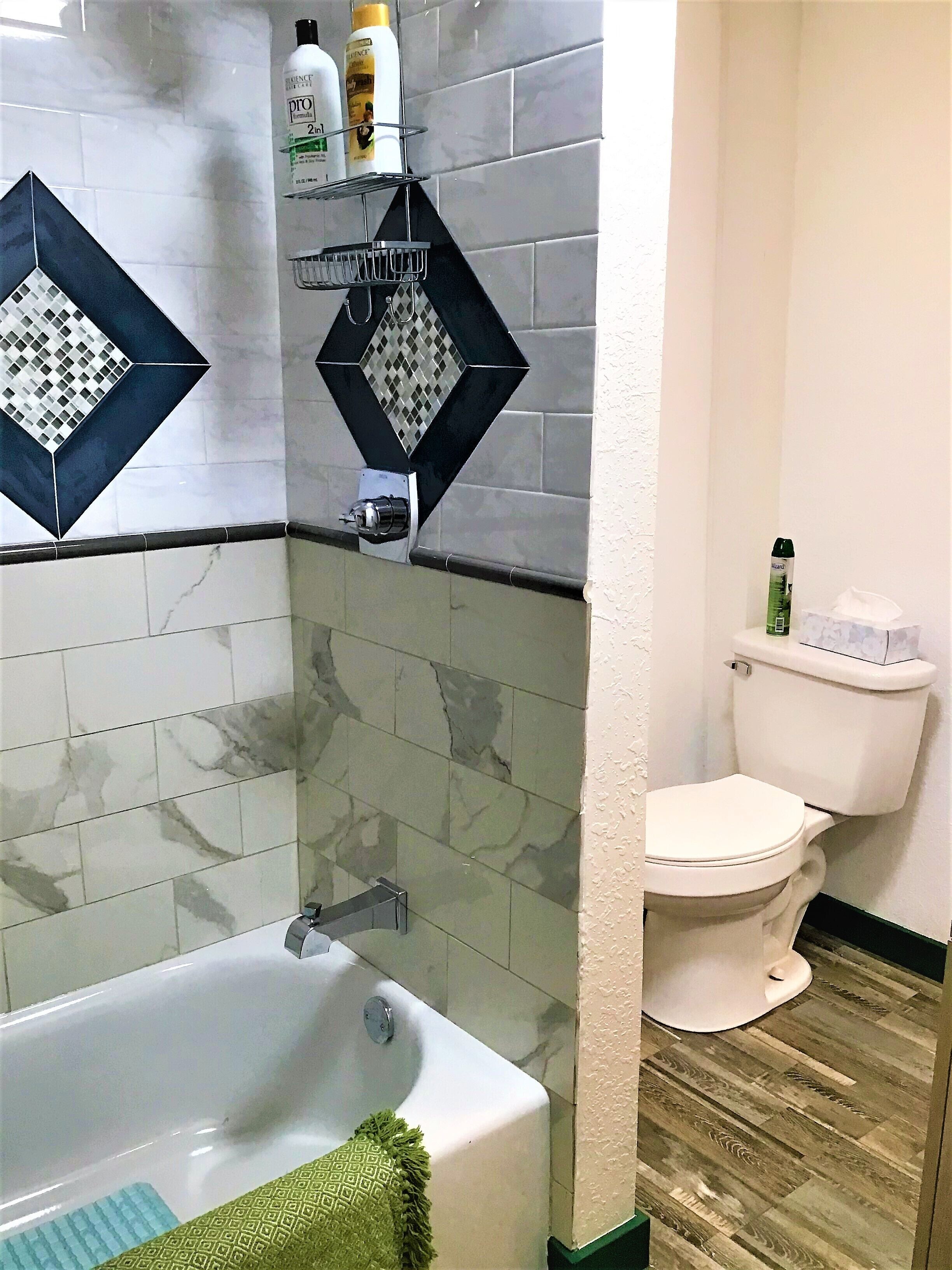A bathroom with a bathtub, toilet, and a shower area.