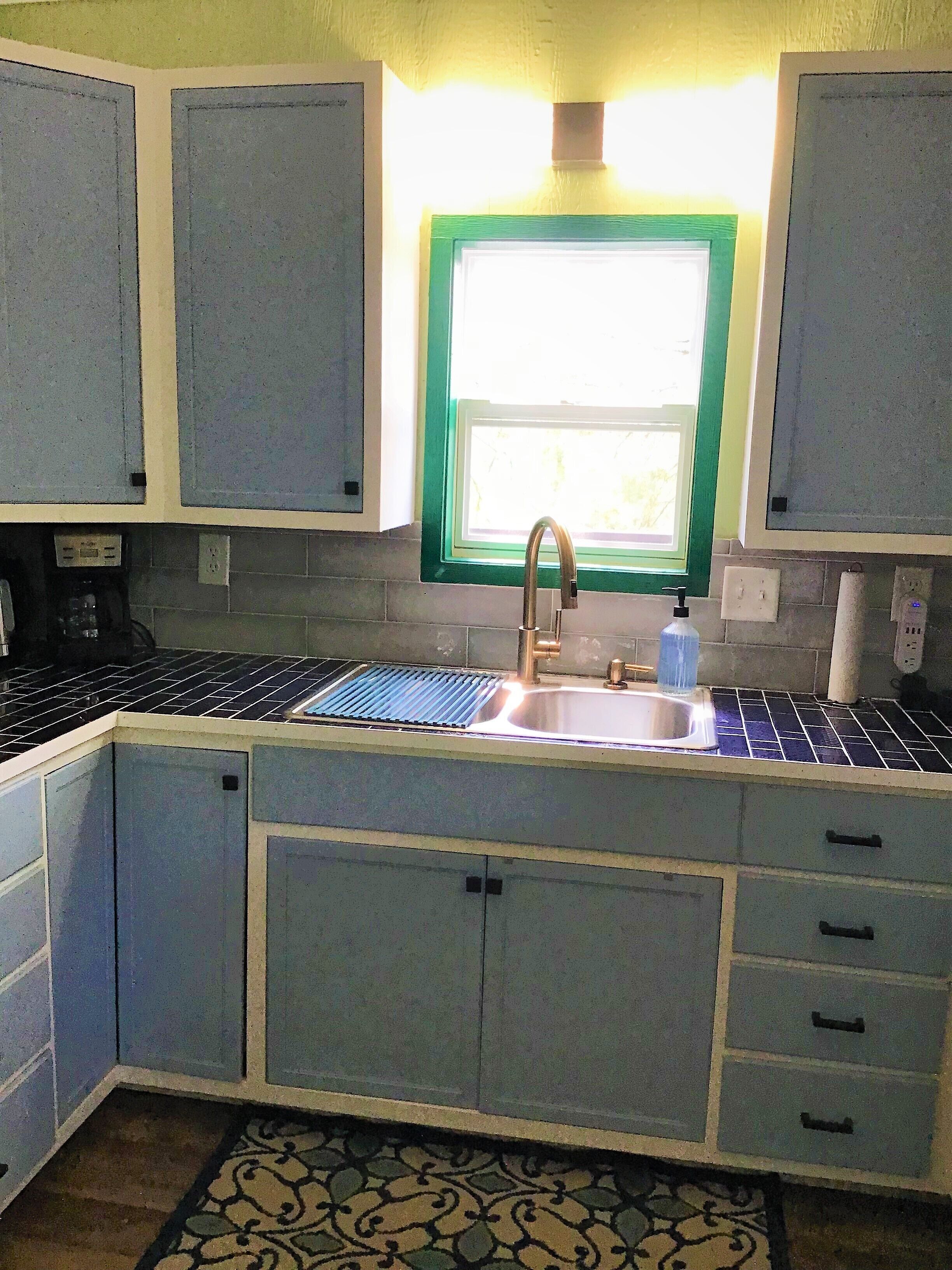 A kitchen with a sink, cabinets, and a window.