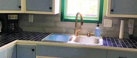 A kitchen with a sink, cabinets, and a window.