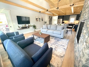 A modern living room with a grey sofa, a wooden coffee table, and a TV mounted on the wall.
