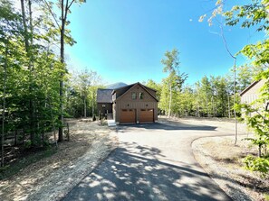 A two-story building with a garage, surrounded by trees and a clear sky.