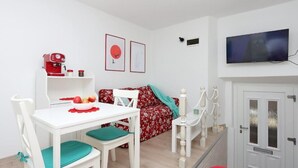 Un espacio habitable compacto con una mesa de comedor, un sofá, un televisor y una cafetera.