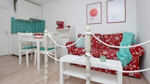 Un espacio habitable compacto con kitchenette, comedor y sofá.