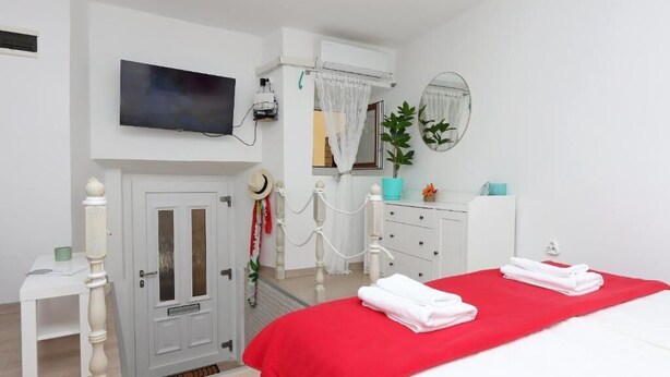 Una habitación de hotel con cama, televisor, armario, escritorio y puerta.