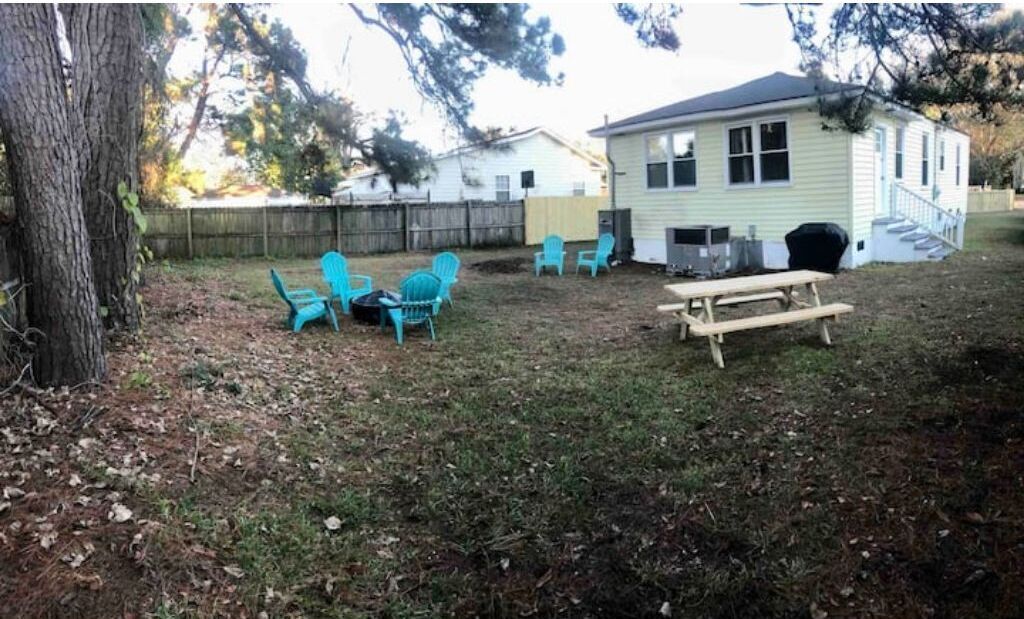 A backyard with a wooden picnic table, two blue chairs, and a small shed.