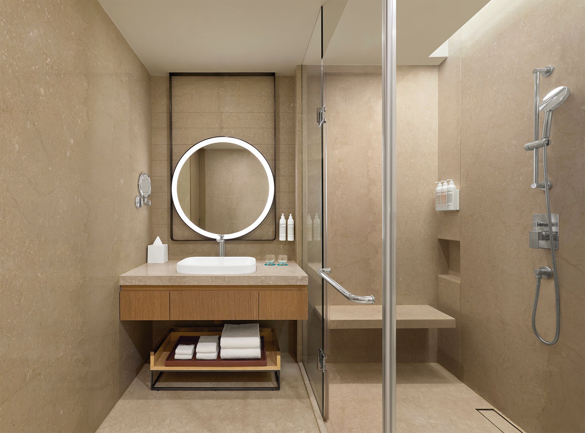 Ein modernes Badezimmer mit einer gläsernen Dusche, einem runden Spiegel und einem Holzbadezimmer.
