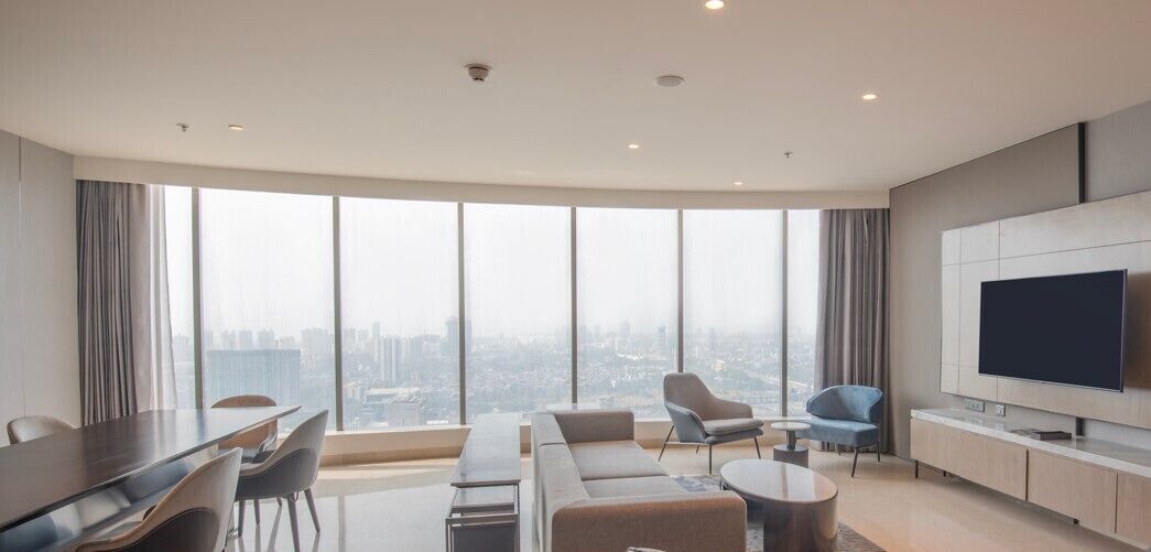 Un salon moderne doté d’un grand téléviseur, de sièges confortables et offrant une vue sur la ville.