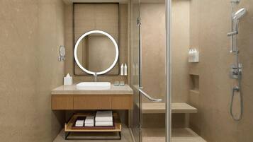 Un baño moderno con cabina de ducha de vidrio, un espejo redondo, un lavabo y un perchero para toallas.