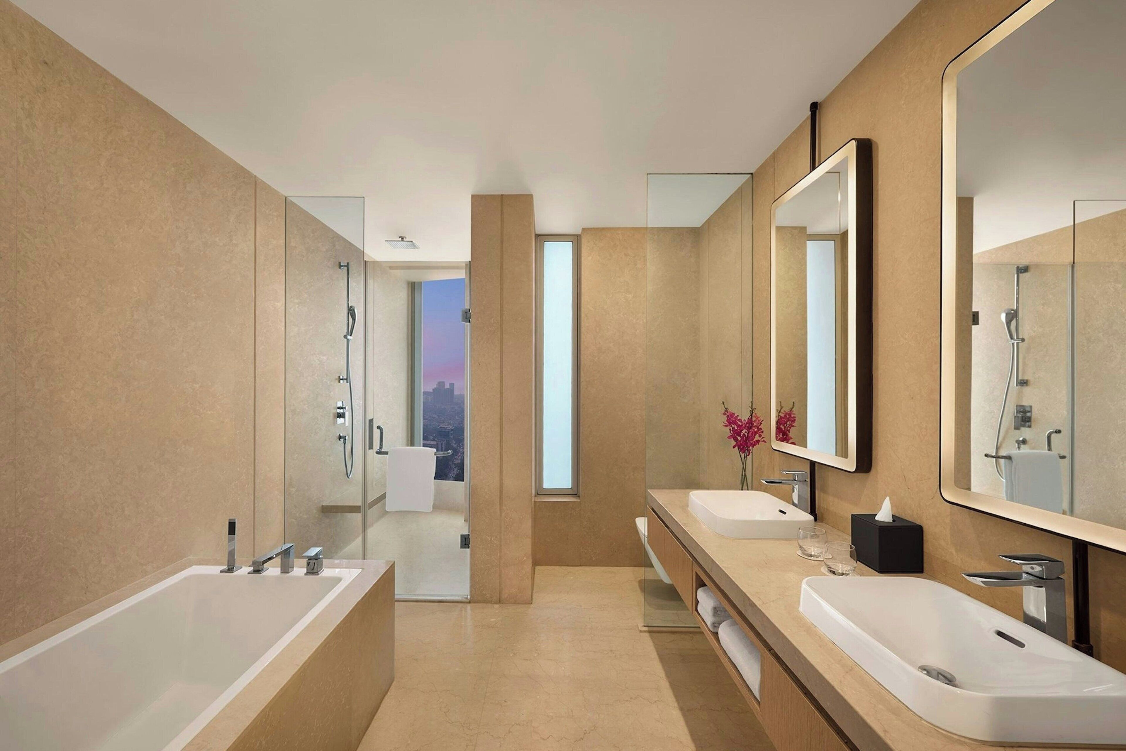 Un baño moderno con dos lavamanos, un espejo grande y una ducha con paredes de cristal.