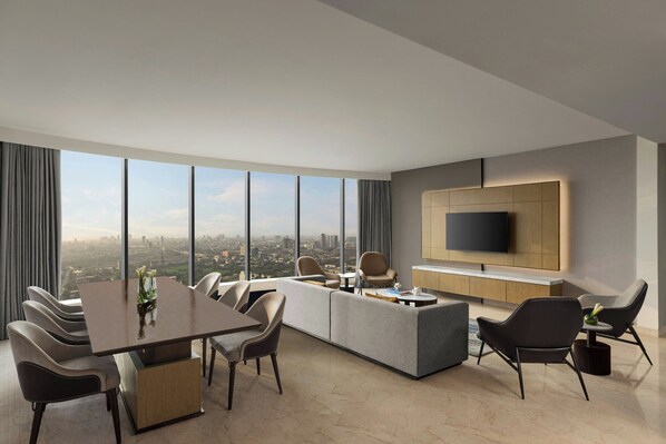 A modern living room with a dining area, a large TV, and a city view. - Le Méridien Navi Mumbai (Navi Mumbai)