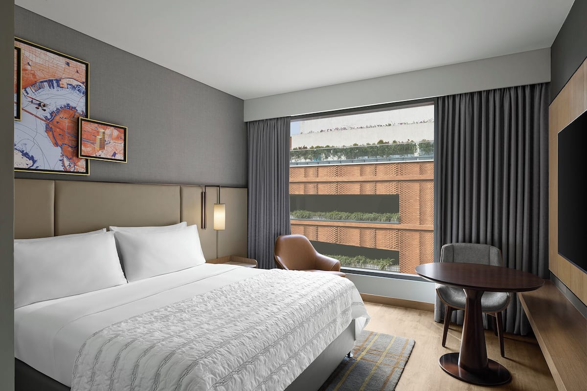 Hotelkamer met een groot bed, een ronde tafel, een stoel, een televisie en een raam met gordijnen.