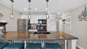 A kitchen with granite countertops, stainless steel appliances, and pendant lighting. - NEW Heated Pool & HOT Tub! Top Floor! Elevator (Galveston)