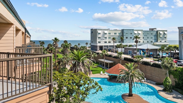 A hotel with a pool, palm trees, and a view of the ocean. - NEW Heated Pool & HOT Tub! Top Floor! Elevator (Galveston)