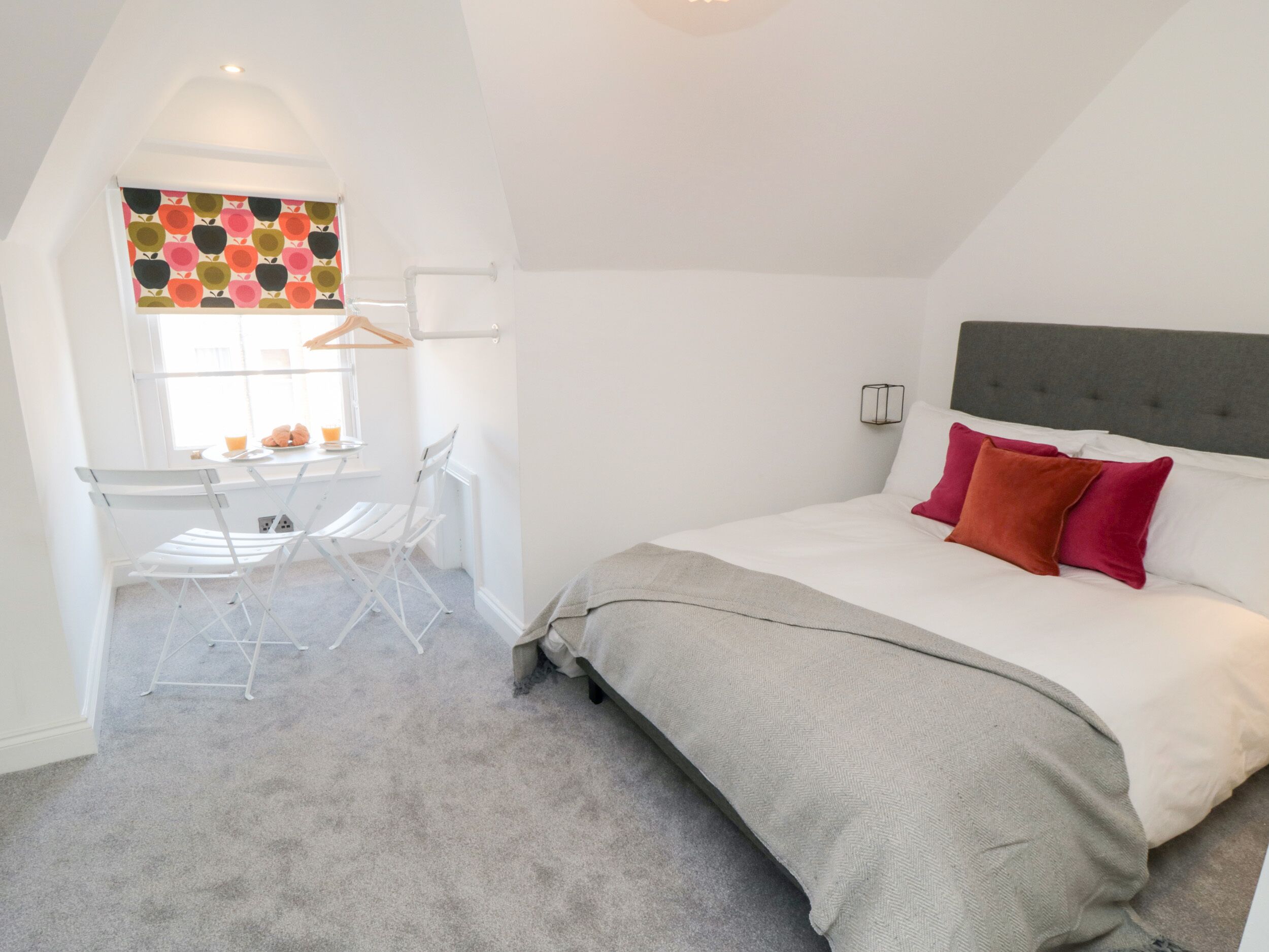 A bedroom with a bed, a desk, and a chair.