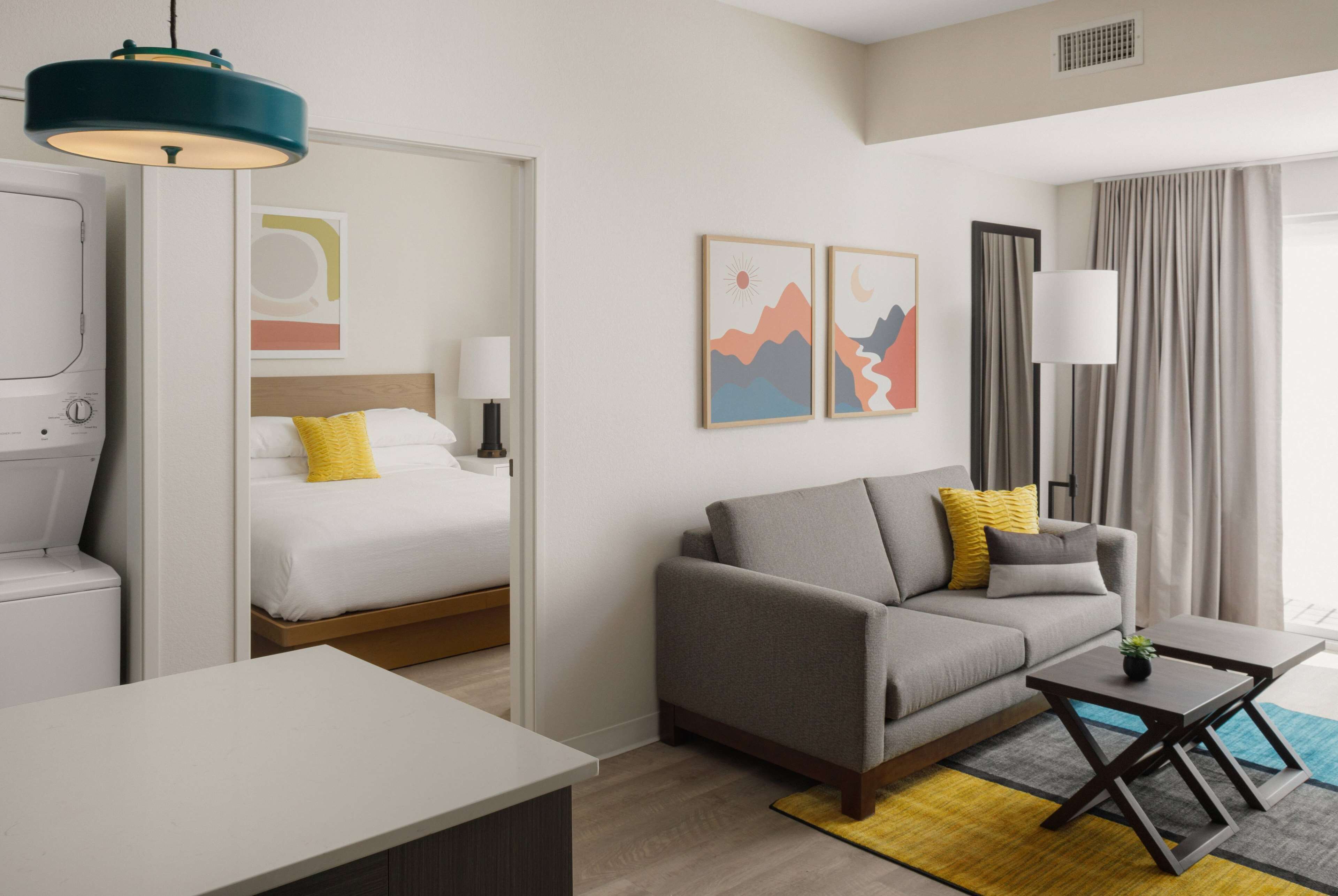A modern hotel room with a bed, sofa, and a small table.