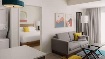 A modern hotel room with a bed, sofa, and a small table.