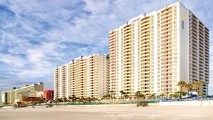 Ein hoch aufragendes Hotel mit mehreren Etagen, Balkonen und Blick auf den Strand.