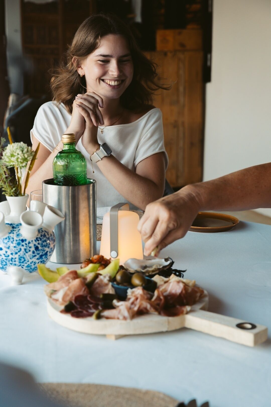 Une personne est assise à une table devant une variété d’aliments, une bouteille et un récipient en métal.