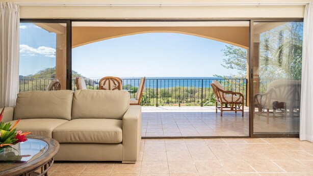 A spacious balcony with a sofa and chairs, offering a view of the ocean. - Oceanview Condo With Pool Near Playa Prieta 2BR - Vida de la Paz 4 (Tempate)