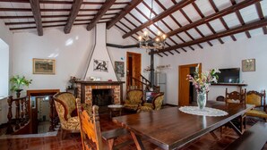 A spacious living room with a wooden dining table, comfortable chairs, a fireplace, and a television. - Cozy home in Catignano with house a mountain view (Catignano)