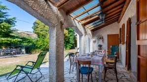 An outdoor patio with stone flooring, wooden tables and chairs, and a covered area with a wooden ceiling and skylights. - Cozy home in Catignano with house a mountain view (Catignano)