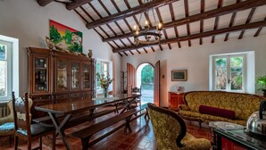 A dining area with a wooden table and benches, a cabinet with glass doors, and a sofa. - Cozy home in Catignano with house a mountain view (Catignano)